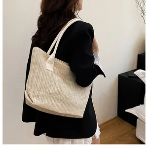Dettaglio ravvicinato della borsa tote intrecciata beige con trama a spina di pesce