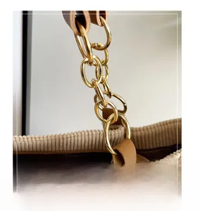 Detail of corduroy tote bag showing golden metal chain strap and leather stitching