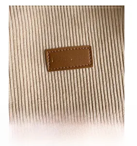 Detailed close-up of corduroy texture and embossed leather 'FASHION' label on the bag