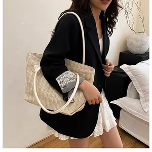 Dettaglio della borsa tote in paglia intrecciata con tracolla in pelle bianca