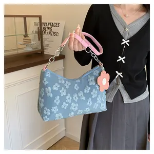 Detail of light blue floral canvas bag with embossed flowers and pink leather strap