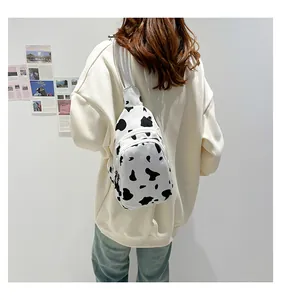 Detail of cow print canvas chest bag with zipper compartments on casual white sweatshirt