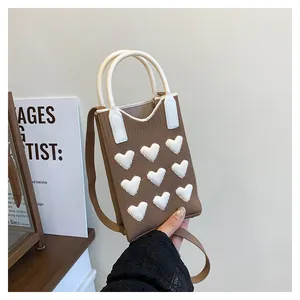 Detail of knitted mini tote with white 3D hearts and cylindrical top handle