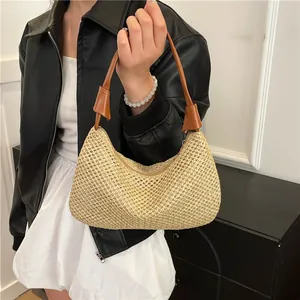 Schicke beige Stroh-Tragetasche mit braunen Lederriemen am Modell für einen trendigen Look