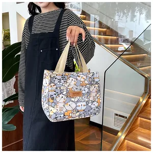Detailweergave van canvas tas met dichte cartoon kattenprints en bruin lederen merklabel