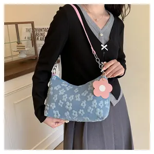 Detail of light blue floral canvas hobo bag with pink leather strap and flower pendant