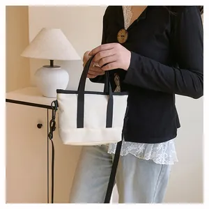 Détail du mini sac bandoulière en toile blanc cassé avec poignées noires et sangle