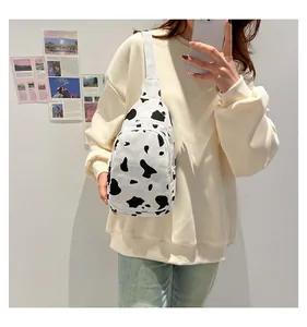 Close-up of a canvas chest bag with cow print pattern worn by a model in a mirror