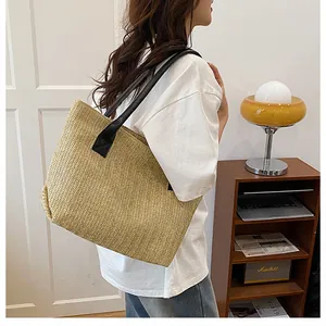 Dettaglio della borsa tote in paglia intrecciata con trama a V e tracolla in pelle nera
