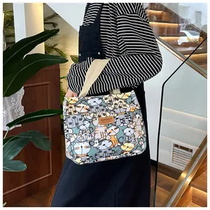 Detailoverzicht van canvas tas met kattenprint en brede schouderband gedragen door model