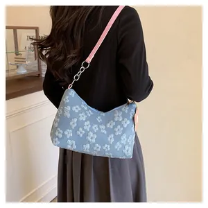Detail of light blue floral canvas bag with pink leather strap shown on a model