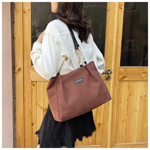 Close-up of deep brown corduroy tote bag with golden chain strap and fashion label