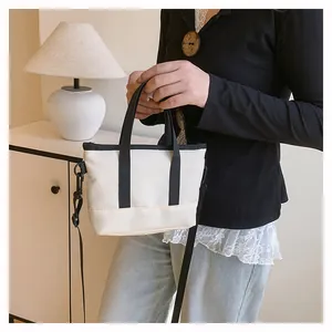 Détail d'un mini sac bandoulière crème avec bordure noire et bandoulière amovible