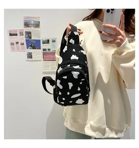 Mirror selfie showing the cow print canvas chest bag with adjustable nylon strap and dual zippers