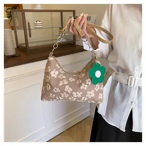 Detail of floral embroidery on light brown canvas shoulder bag with chain strap