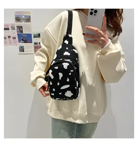 Detail of cow print canvas chest bag with adjustable strap worn by model