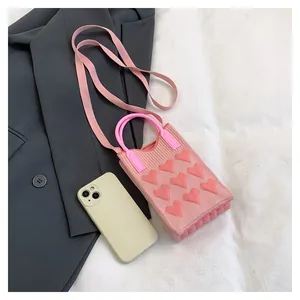Close-up of pink knitted mini bag with heart patterns on a stylish grey blazer background