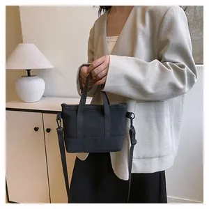 Détail du sac fourre-tout noir en toile avec bandoulière réglable et anses solides