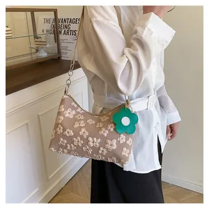 Detail of floral embroidery on beige canvas tote bag with a green flower charm