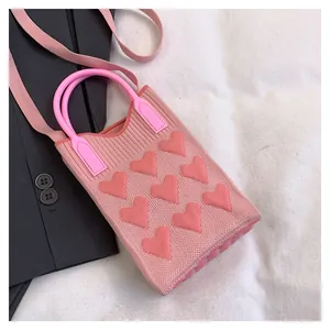 Close-up of pink knitted phone bag with 3D heart decorations and round resin handles