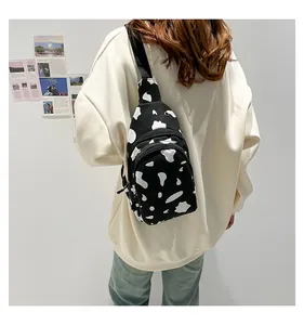 Close-up of cow pattern canvas chest bag on model with double zipper and black strap