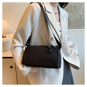 Gros plan d'un sac bandoulière noir montrant le nylon texturé et les détails du logo
