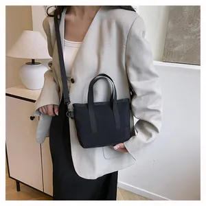 Détail d'un petit sac bandoulière noir en toile porté avec un blazer beige élégant