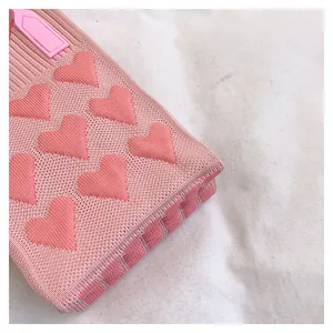 Detail of pink knitted mini bag showing textured heart jacquard and durable handle