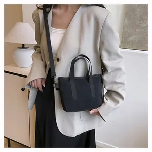 Mini sac cabas noir en toile avec bandoulière réglable porté par un mannequin femme