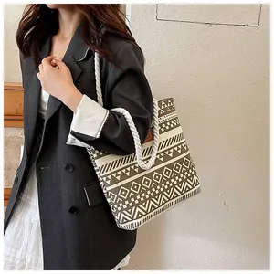 Tragebeispiel einer braunen Canvas-Tasche mit geometrischem Muster und Kordelgriff