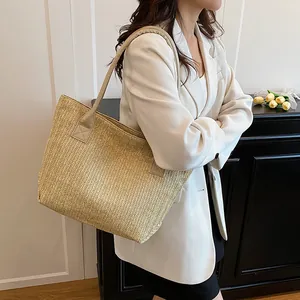 Borsa tote in paglia intrecciata con manici in pelle beige indossata da una modella