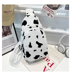 Detail of cow print canvas chest bag with dual zippers and adjustable shoulder strap