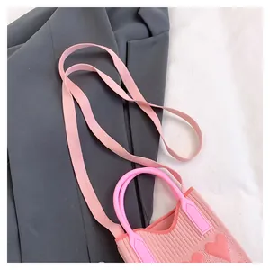 Pink rib-knitted mini bag with heart pattern details on grey blazer and white fabric