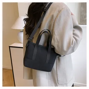 Mini sac bandoulière noir en toile porté par un mannequin dans un intérieur au style épuré