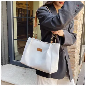 Detail of corduroy tote bag featuring leather shoulder strap and fashion brand logo label