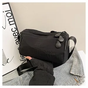 Détail du sac bandoulière en nylon noir avec logo DUONING et fermetures éclair en goutte