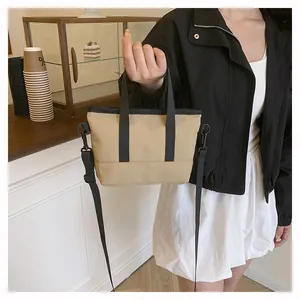 Détail d'un mini sac bandoulière kaki avec poignées noires et bandoulière réglable