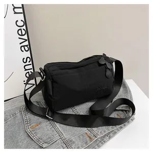 Détail du sac bandoulière noir avec sangle large et logo DUONING embossé sur tissu en nylon