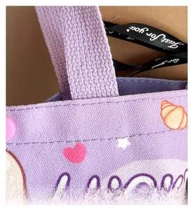 Detail of purple canvas tote bag with thick strap, heart print and snap button closure