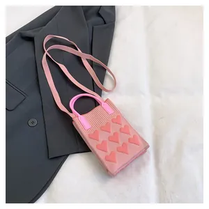 Detail of pink knitted mini bag with heart appliques on a grey blazer background