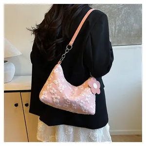 Detail of pink floral embroidery texture and leather strap on a canvas tote bag