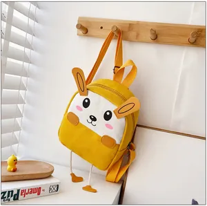 Gros plan d'un sac à dos en toile jaune avec oreilles de lapin 3D sur cintre en bois