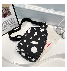 Flat lay view of a cow print canvas chest bag with adjustable strap and lifestyle props