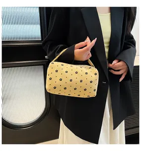 Close-up of yellow corduroy floral pouch with heart patterns held by a hand