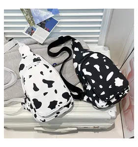 Detail of cow print canvas chest bags in black and white shown on a travel suitcase