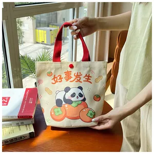Detail of cute panda and persimmon canvas tote bag with red handles in a home setting