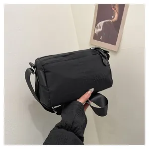 Gros plan d'un sac bandoulière noir avec lettrage embossé sur tissu haute densité