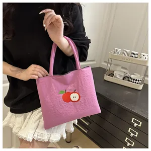 Close-up of pink canvas tote bag with red apple embroidery patch in a home setting