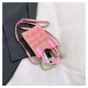 Detailed close-up of pink knitted mini crossbody bag with 3D heart and round rubber handle