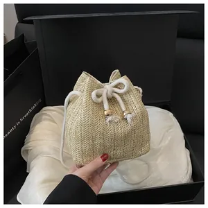 Detail of woven straw bucket bag with cotton drawstring closure and decorative tassels